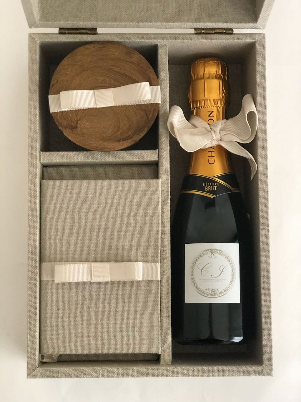 Detalhe do interior da caixa forrada com livrinho, chandon e vela perfumada